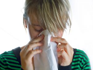 girl sneezing into tissue